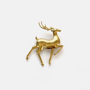 Detailed close-up of a golden reindeer brooch with a polished mirror finish on a white background