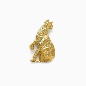 Macro detail of a vintage golden cat brooch with intricate geometric textures