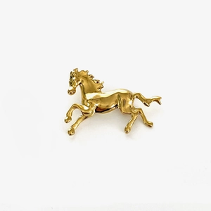 Detailed close-up of a vintage golden running horse brooch with polished metal finish