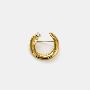 Detail view of a gold C-shaped stainless steel brooch with a white pearl accent