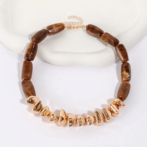 Detail of brown marble resin cylinder beads and golden geometric metal charms on necklace