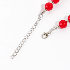 Detail of red faux pearl necklace featuring silver lobster clasp and extension chain