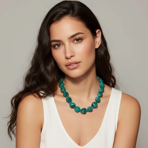 Primo piano di una collana con grosse perle marmorizzate verde scuro indossata da una modella