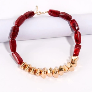 Detail of irregular golden metal beads and red-brown marbled resin cylinder necklace