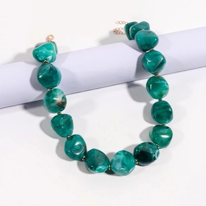 Dettaglio della collana con pietre verde smeraldo effetto marmo e chiusura dorata