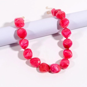 Dettaglio della collana con pietre irregolari rosse effetto marmo e maglie in metallo oro