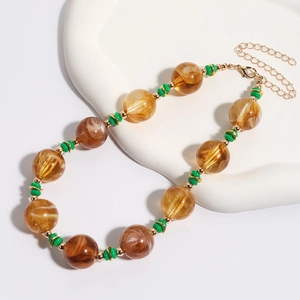 Macro-opname van vintage amberkleurige kralen met groene tussenringen en gouden sluiting