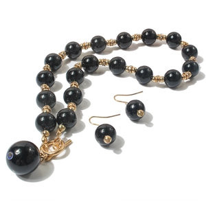 Dettaglio della collana di perle nere con accenti dorati e ciondolo occhio del male