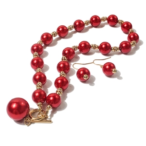 Dettaglio parure collana e orecchini con perle rosse e accenti in strass dorati
