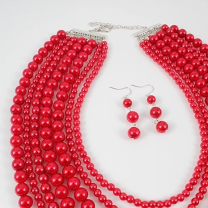 Détail d'un collier à plusieurs rangs de perles rouges et boucles d'oreilles assorties