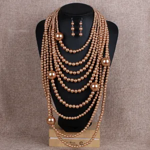 Detailed view of multilayer champagne pearl necklace and earring set on a black mannequin