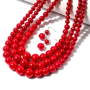 Ensemble collier de perles rouge multicouche et boucles d'oreilles sur support blanc