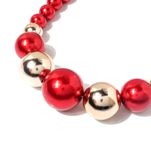 Dettaglio di eleganti perle metalliche rosse e dorate su una collana girocollo chic