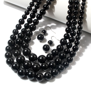 Gros plan sur collier de perles noires dégradées multicouche et boucles d'oreilles