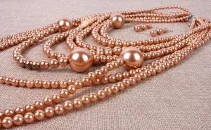 Detailed close-up of multi-layer champagne faux pearl necklace and matching earrings