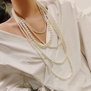 Détail d'un collier de perles blanches multicouches avec un chemisier blanc à col en V