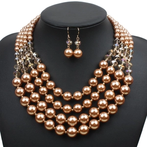 Detailed close-up of a five-layer champagne faux pearl necklace and earring jewelry set