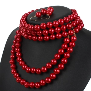 Macro shot of layered red faux pearl necklace and matching drop earrings on a black neck model