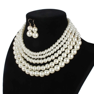 Detailed view of layered faux pearl necklace set on black velvet mannequin