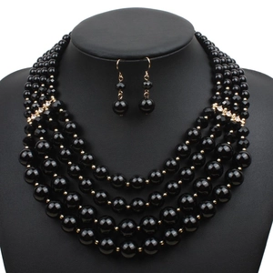 Close-up of five-layer black bead necklace and hook earrings set with gold rhinestone accents