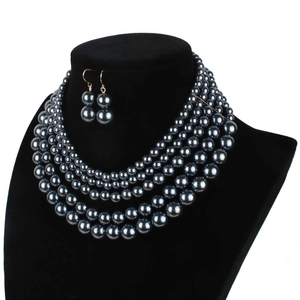 Close-up of four-layer faux pearl necklace and matching earrings on black neck bust