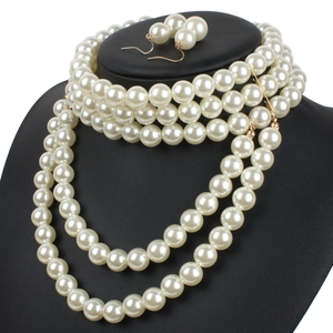 Close-up of multi-layer faux pearl necklace and gold hook earrings on black stand