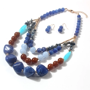 Dettaglio di un set di collane bohémien a tre strati con perle di resina blu e rosse