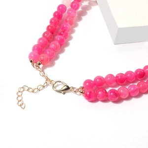 Detail van dubbellaagse roze kralenketting met gouden karabijnsluiting en verlengketting