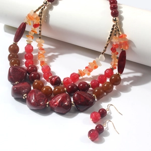 Dettaglio della collana di perline a più strati e orecchini in resina rossa bohémien