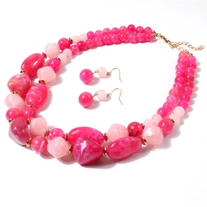 Detail van roze marmeren hars kralen en gouden waterdruppel hanger op dubbellaagse ketting