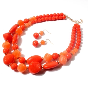 Detail van een dubbellaagse feloranje kralenketting met bijpassende druppeloorbellen