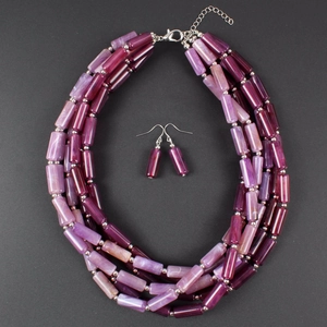 Detalle macro de cuentas cilíndricas de resina púrpura y magenta en collar de varias capas