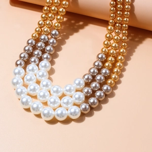 Detail van een meerlaagse parelketting met witte, gouden en grijze parels