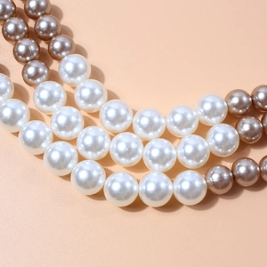 Elegante gelaagde parelketting in wit en champagne op een gladde achtergrond