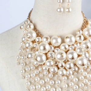 Macro shot of layered faux pearl necklace with gold floral accents and matching earrings