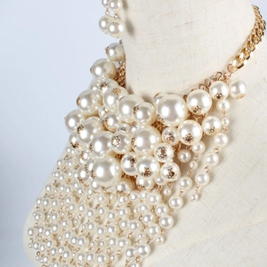 Detailed view of layered faux pearl fringe necklace with golden floral spacers on a bust