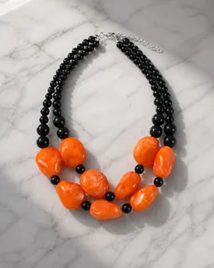 Detalle de collar de doble capa con cuentas de resina naranja y pequeñas cuentas azul marino