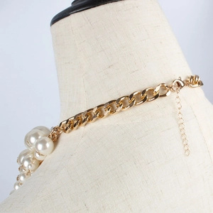 Detailed view of chunky gold chain and large faux pearl link necklace with lobster clasp