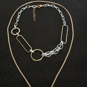Detail of layered gold and silver necklace with large metal rings and textured chain