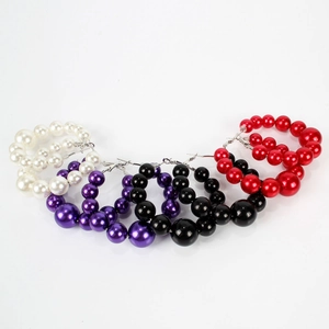 Dettaglio di grandi orecchini a cerchio con perle lucide in bianco, viola, nero e rosso