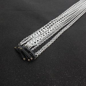 Detail of silver tassel hair chain extensions with black BB clips on a dark background