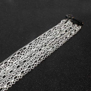 Detail of multi-layered silver tassel hair chains with black metal clip on glitter background
