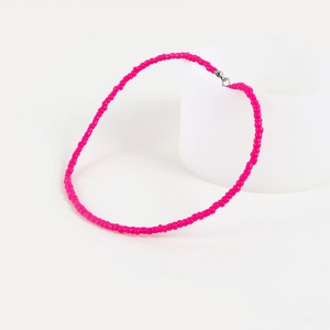 Detail of rose red beaded choker with silver lobster clasp on white cylindrical stand