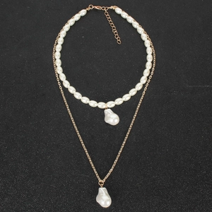Dettaglio di collana dorata a due strati con perle barocche bianche su sfondo nero