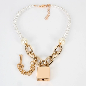 Detalle de collar de perlas y cadena dorada con colgantes en forma de candado cuadrado y llave