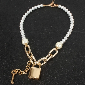 Detalle del colgante de candado dorado y collar de perlas sobre fondo negro texturizado