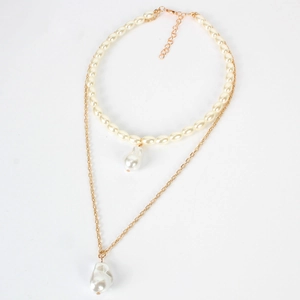 Dettaglio macro della collana a doppio strato dorata con pendenti di perle barocche e catena