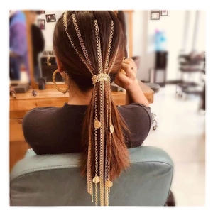 Detailed view of long gold tassel hair chain extensions with metallic sequins on ponytail