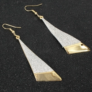 Vista dettagliata di orecchini geometrici bicolore in oro e glitter argento su velluto