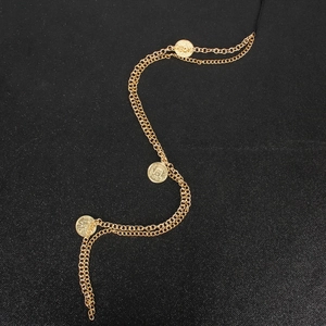 Double-layer gold hair chain with vintage coin pendants on a black textured background